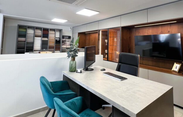 Beratungsplatz im Küchenstudio auf Mallorca – Blau bepolsterte Sessel vor einem tisch in Granitsteinoptik.