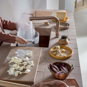 Kupferfarbener Quooker Kochendwasserhahn aus Metall mit gebogenem Auslauf, liefert heißes Wasser direkt zum Kochen und Befüllen von Töpfen in moderner Küche