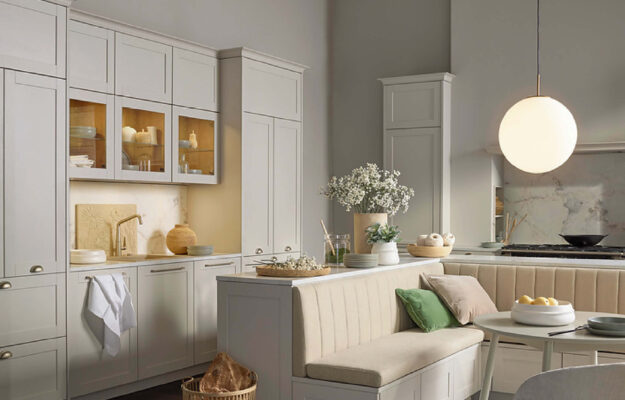 Nolte Landhausküche in eleganter, heller Ausführung mit klassischen Fronten, integrierter Sitzbank und stilvoller Beleuchtung für ein wohnliches Ambiente